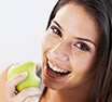 Woman happily biting apple after receiving dental services in Buckhead Atlanta